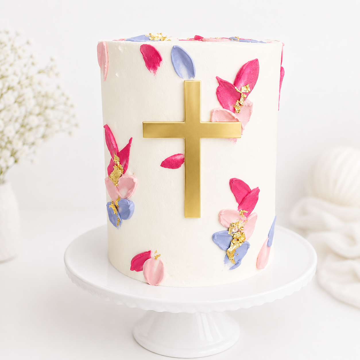 Decorative cake with floral designs and a gold cross on a white background