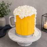 Beer mug cake with white foam on a marble stand against a gray background