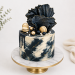 Decorative cake with black and gold design on a marble stand