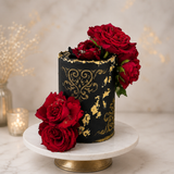 Decorative black container with gold patterns and red roses on a marble surface.