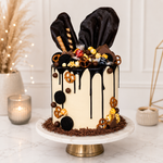 Decorative cake with chocolate drizzle and festive decorations on a marble stand.