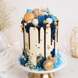 Decorative cake with chocolate drizzle, blue and gold elements on a white background