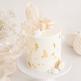 White cake with gold accents and decorative elements on a white plate.