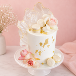 Decorative cake with flowers and gold accents on a pink background