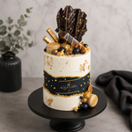 Decorative cake with chocolate and gold elements on a stand against a neutral background