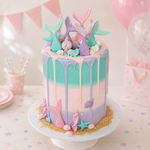 Pastel-colored cake with mermaid tails and ocean-themed decorations on a white plate.