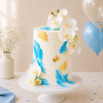 Decorative cake with blue and gold abstract patterns and white flowers on a white stand.