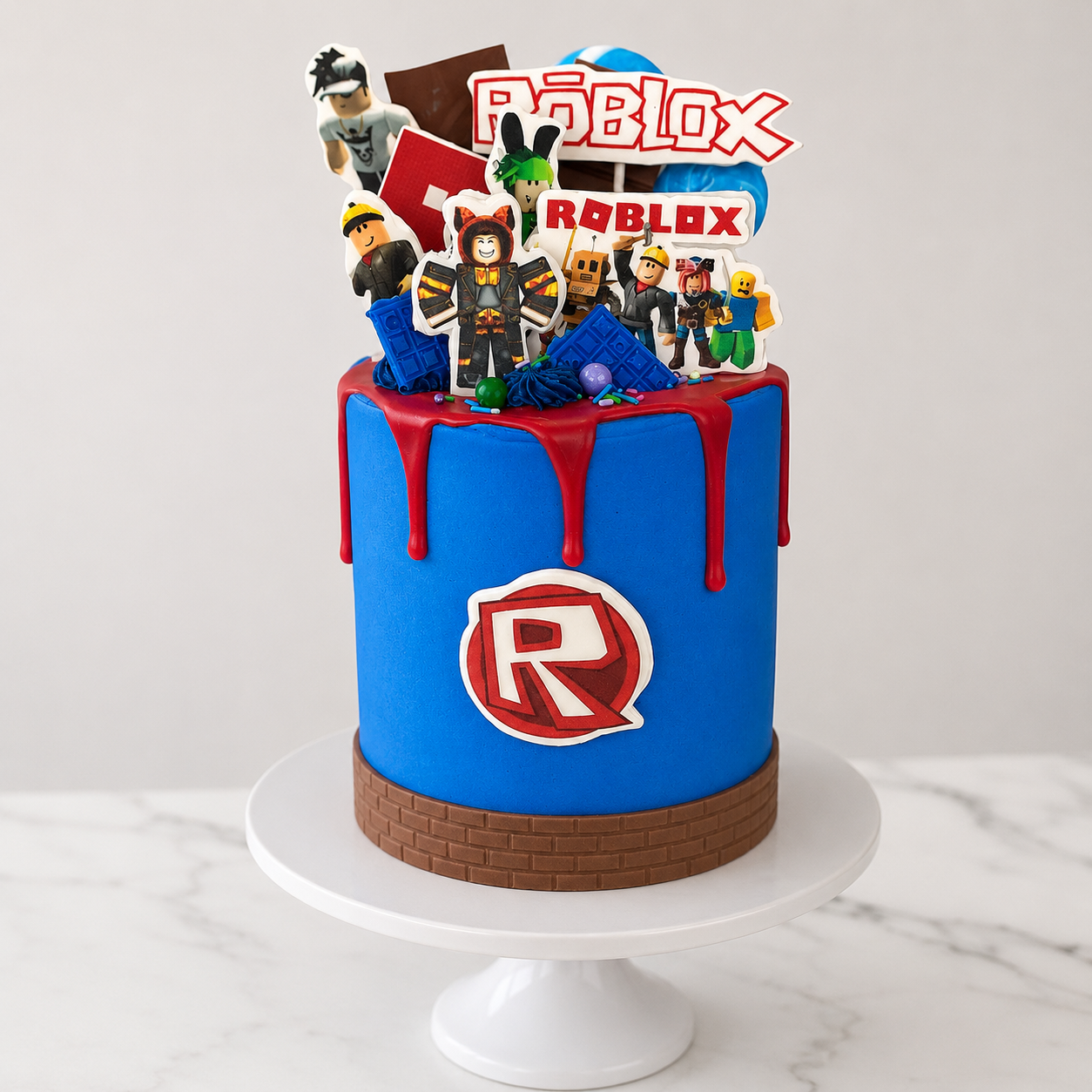 Roblox-themed birthday cake with character figures and colorful design on a white marble surface.