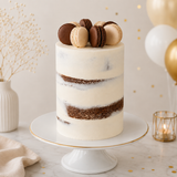 Layered cake with macarons on top, placed on a white cake stand with gold accents.