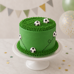Green cake with soccer ball decorations on a white stand, surrounded by party decorations.