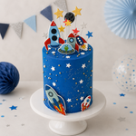 Blue space-themed cake with rocket designs on a white stand, decorated with stars and planets.